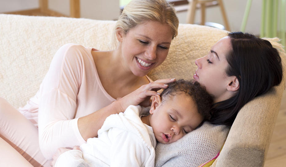 Female couple cuddling a baby